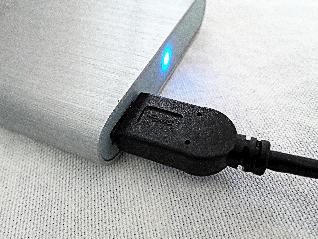 Zewnętrzny dysk twardy podłączony kablem USB do komputera jako nośnik kopii zapasowej.