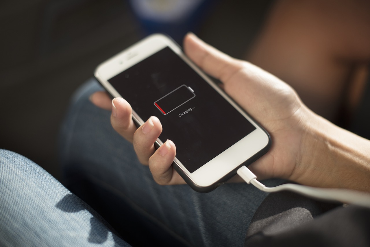 Smartfon z niskim poziomem baterii ładowany w dłoni trzymającej telefon